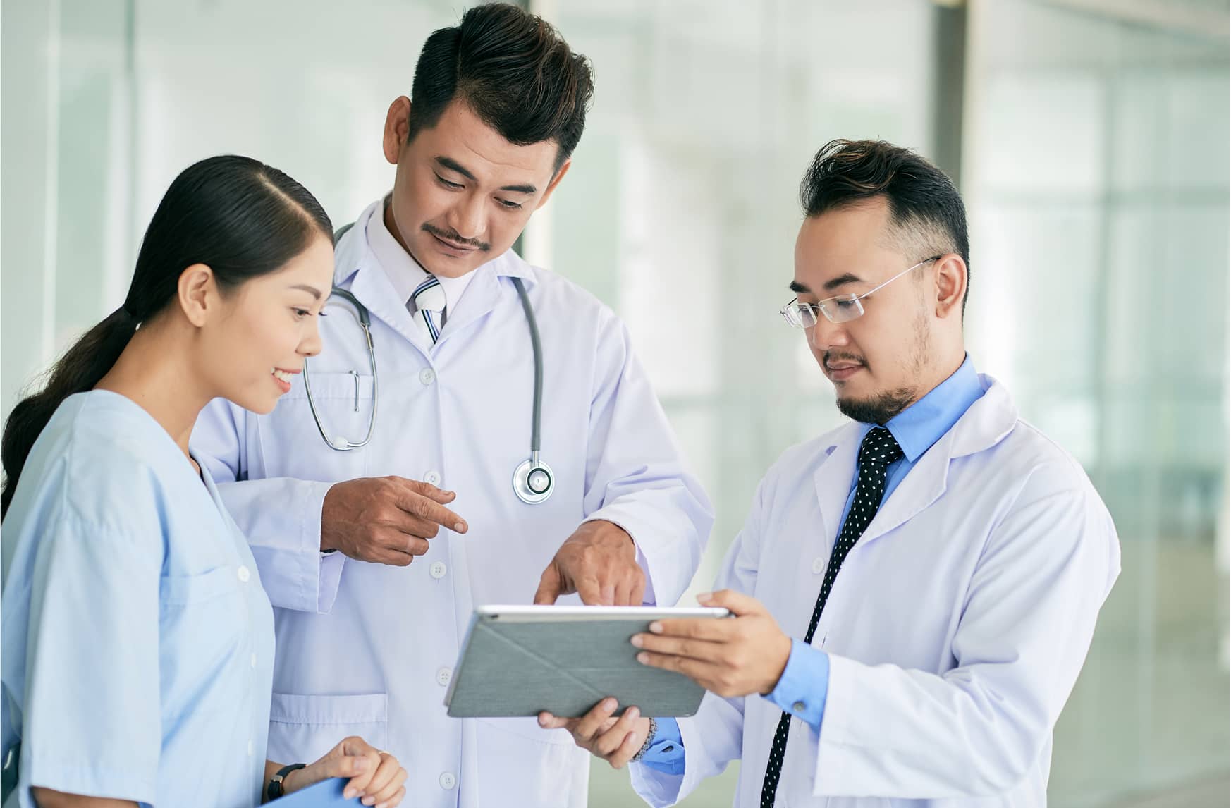 Two doctors and a nurse reviewing a tablet