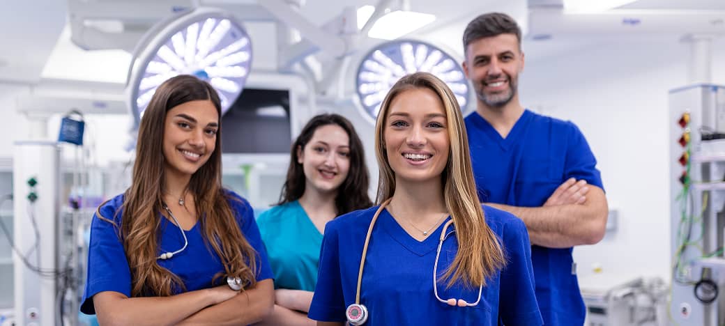Four nurses in an OR smiling at the camera